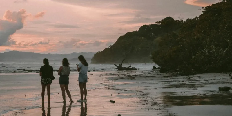 Tre persone in spiaggia al tramonto in Costa Rica, immersioni con squali