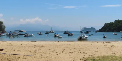 Vista da una spiaggia di Ilha Grande con barche e una nave da crociera