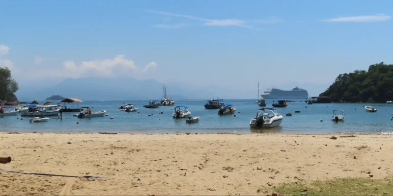 Vista da una spiaggia di Ilha Grande con barche e una nave da crociera