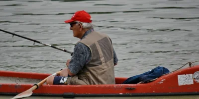 Uomo con una canna da pesca in un kayak rosso sull’acqua