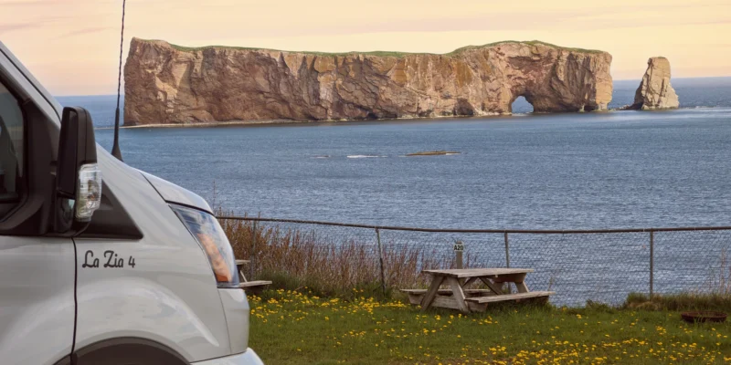 Furgone camperizzato e tavolo da picnic sulla costa con vista sulla roccia di Percé in Québec
