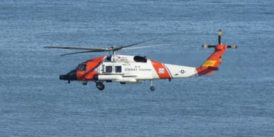 Elicottero bianco e arancione della Guardia Costiera statunitense in volo sul mare blu. Foto illustrativa d’archivio del 2021; non mostra il salvataggio al largo di Ensenada dell’ottobre 2026.
